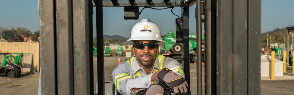 Man assisting another worker with his harness on jobsite