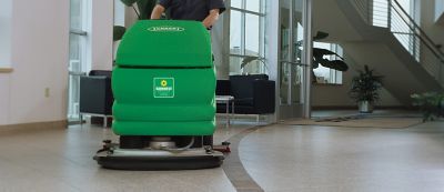 Sunbelt Rentals worker pushing a floor scrubber. 