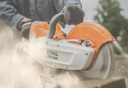 A person wearing black gloves while using a circular saw to cut wood.