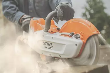 A person wearing black gloves while using a circular saw to cut wood.