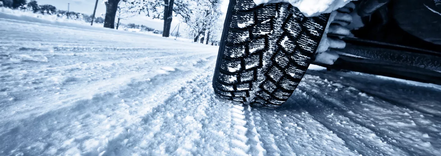 A close-up view of a tire's tread driving over a snowy road.