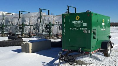 An indirect-fired heating unit installed at a job site, surrounded by snow.