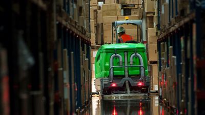 Someone driving an industrial floor scrubber in a warehouse.