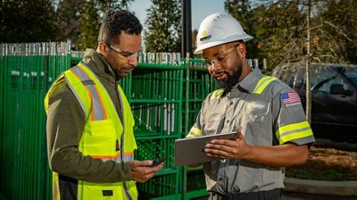 Two people in safety apparel engaged in conversation at a construction site.