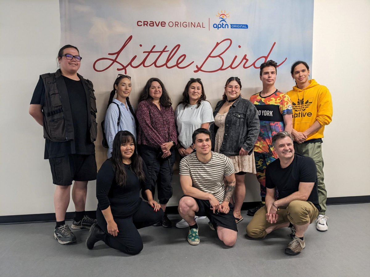 A group standing in front of a Little Bird film banner.