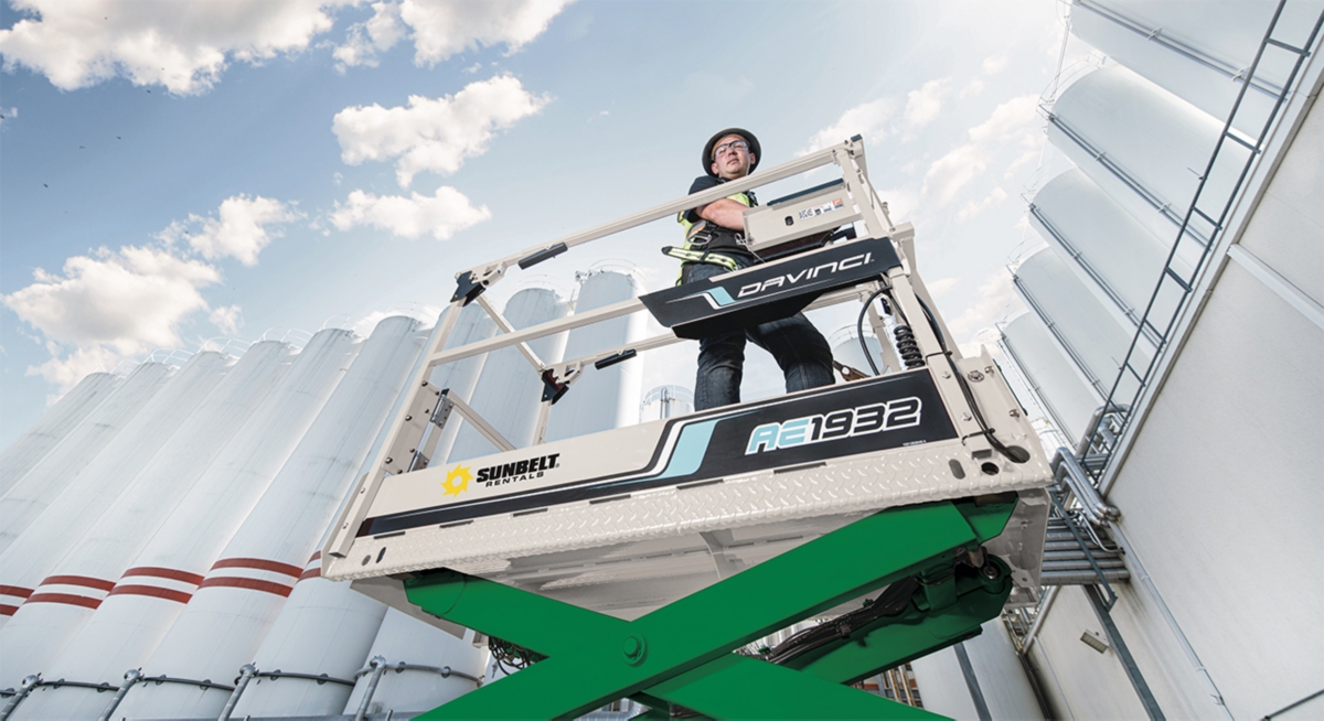 A closeup view of someone on a scissor lift at an industrial job site.