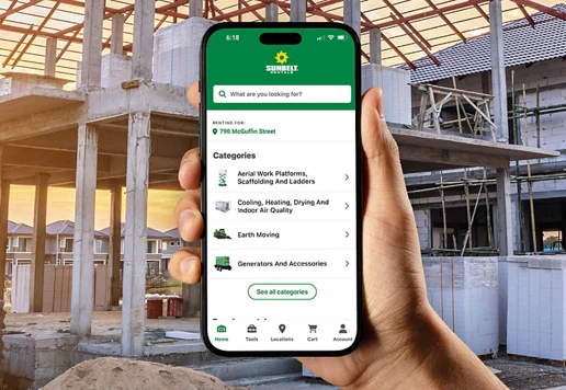 A close-up view of someone holding a phone with the Sunbelt Rentals mobile app. A construction site is in the background.