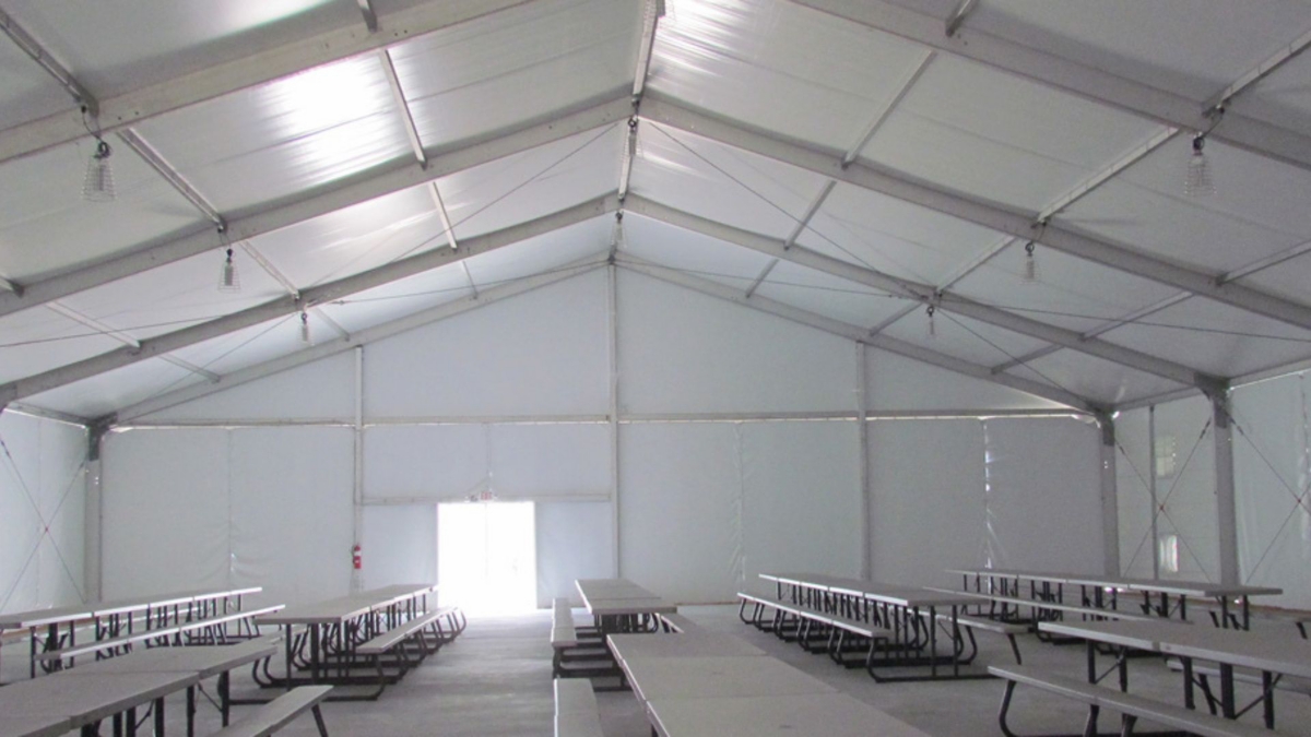 The interior of a temporary fabric structure with lunch tables.