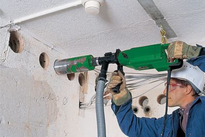 Someone wearing a safety helmet using a power core drill.