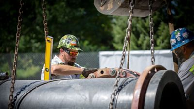 People wearing helmets and sunglasses work around pumps.