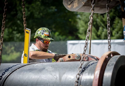 People wearing helmets and sunglasses work around pumps.