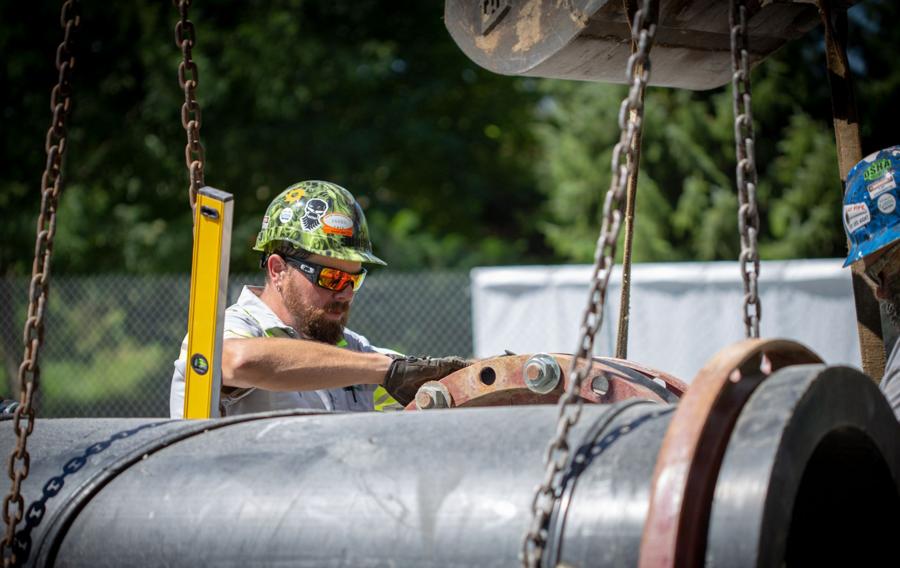 People wearing helmets and sunglasses work around pumps.