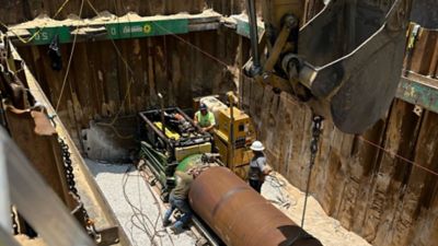 People in a trench testing pipes.