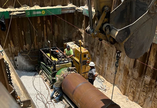 People in a trench testing pipes.