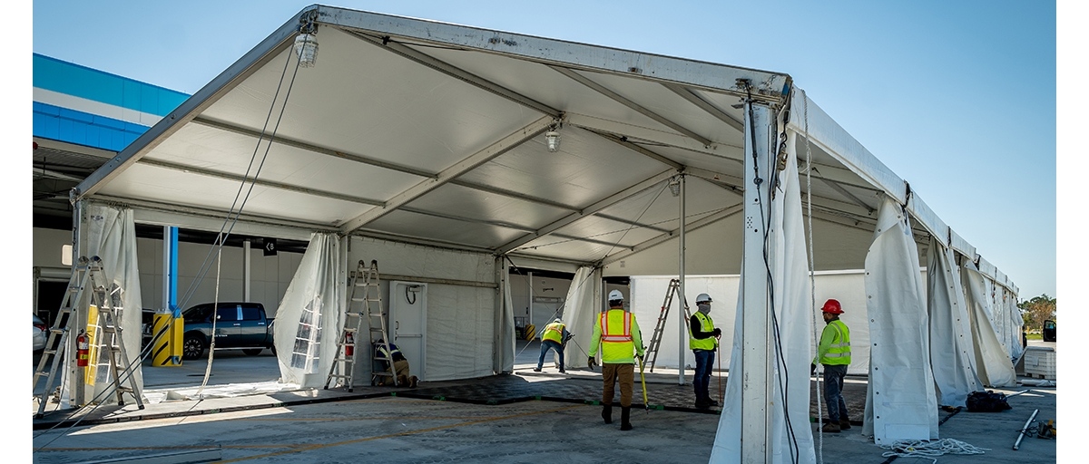 People working around a temporary structure assembled for a pop-up healthcare site.