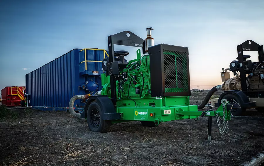 A high head pump from Sunbelt Rentals on a dirt lot, alongside other equipment.