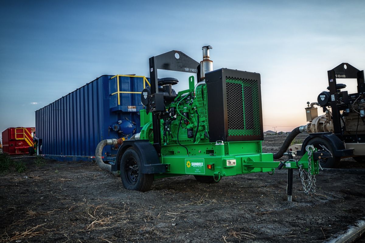 A high head pump from Sunbelt Rentals on a dirt lot, alongside other equipment.