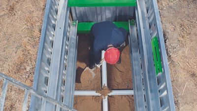 Trench worker in PPE setting up a tripod