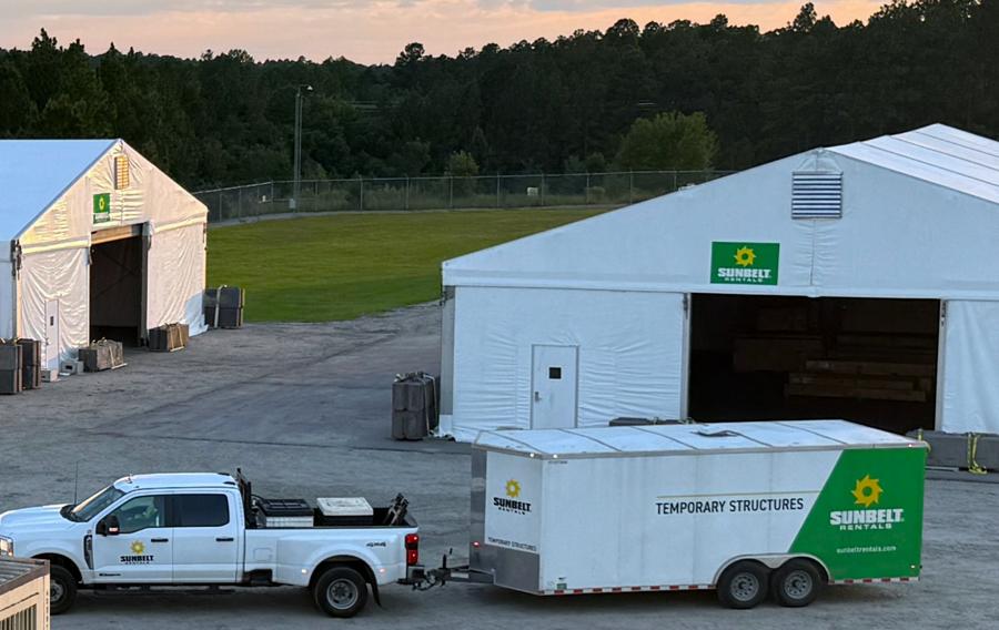 Several large temporary structures set up in a gravel lot.