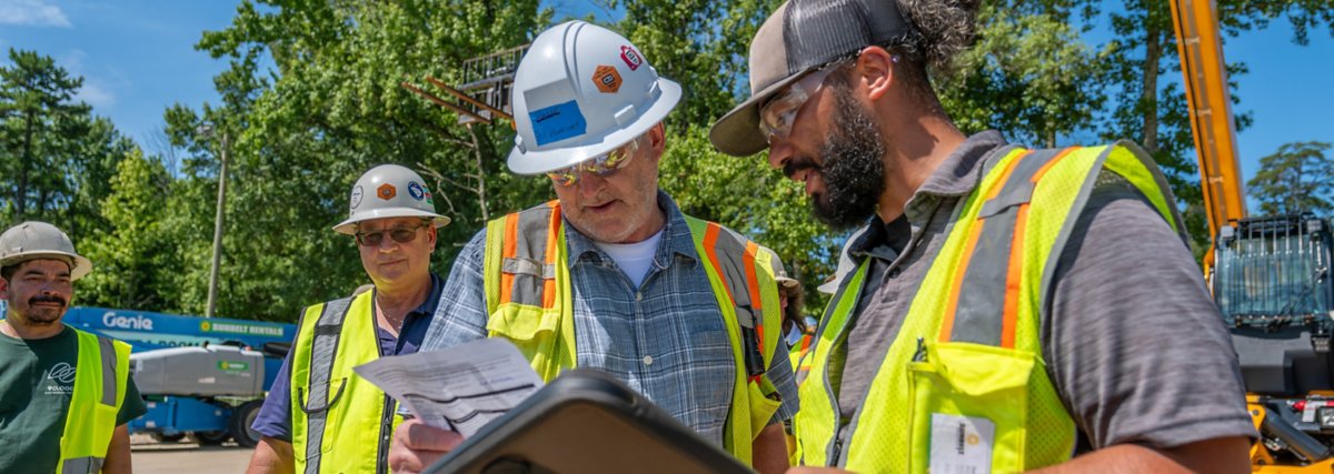 A group of people wearing safety apparel conversing at a job site.