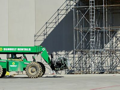 A forklift carrying scaffolding equipment.