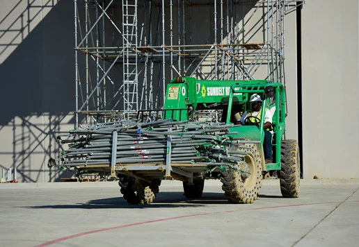 A forklift carrying scaffolding equipment.