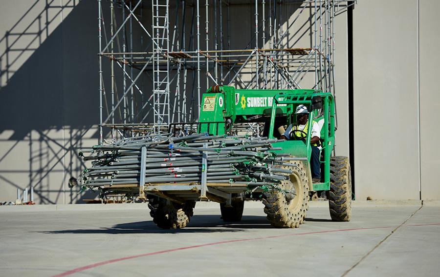 A forklift carrying scaffolding equipment.