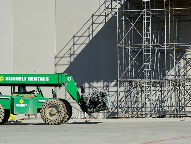 Scaffolding on side of building next to a forklift.