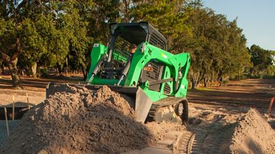 A skid steer moving dirt at a jobsite.