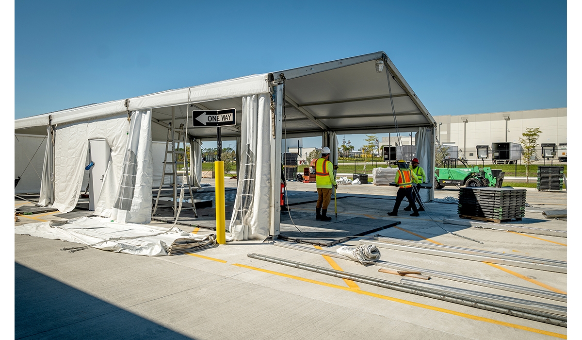 Several workers in safety vests assembling a large temporary structure.