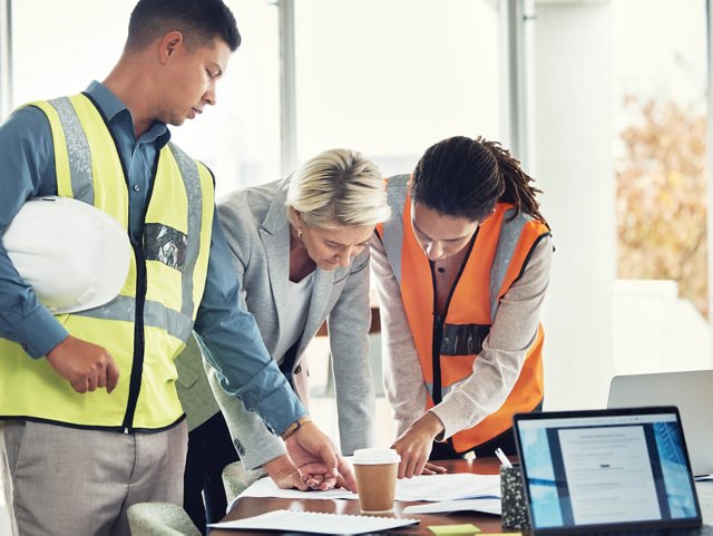A team of three people standing at a table, planning.