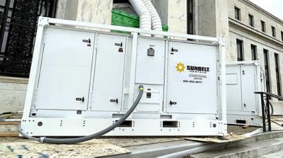 A large temporary air conditioning unit from Sunbelt Rentals installed in front of a building.