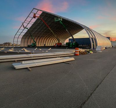 A temporary structure being erected by workers using three aerial platforms.