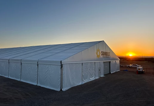 A fabric structure from Sunbelt Rentals at a job site, during sunrise.