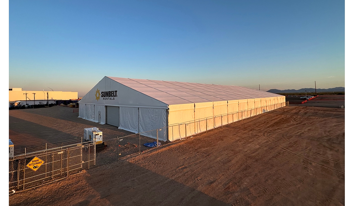 A temporary structure from Sunbelt Rentals on a dirt lot outside during sunset. 