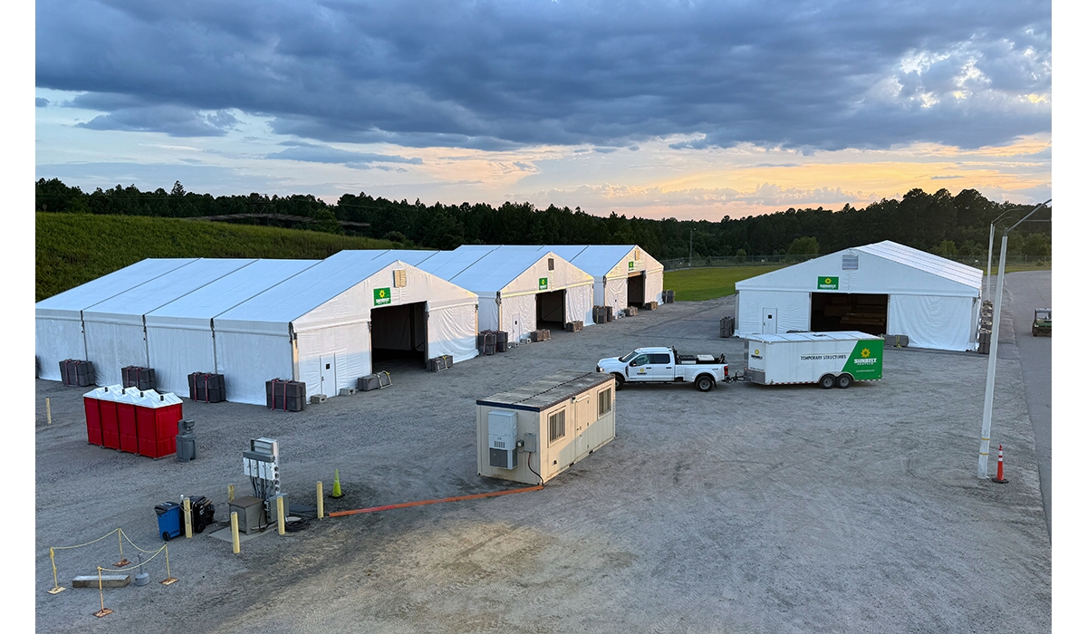 Several large temporary structures set up in a gravel lot.