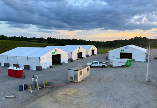 Several large temporary structures set up in a gravel lot.