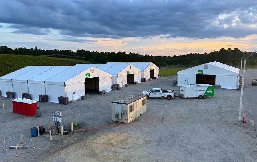 Several large temporary structures set up in a gravel lot.