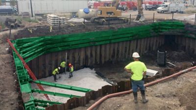 People wearing safety apparel work in and around a sheet and frame system.