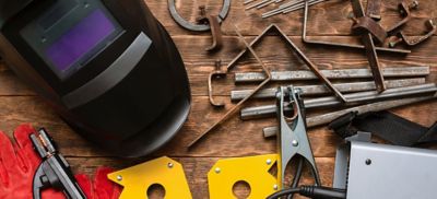 An array of welding tools sitting on a wooden table.