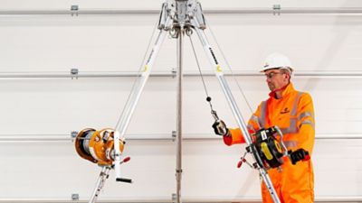 A person wearing safety apparel holding fall protection lanyards.