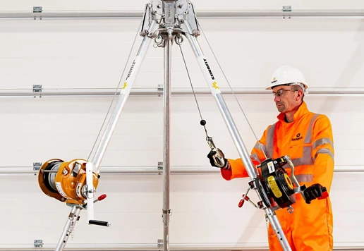 A person wearing safety apparel holding fall protection lanyards.