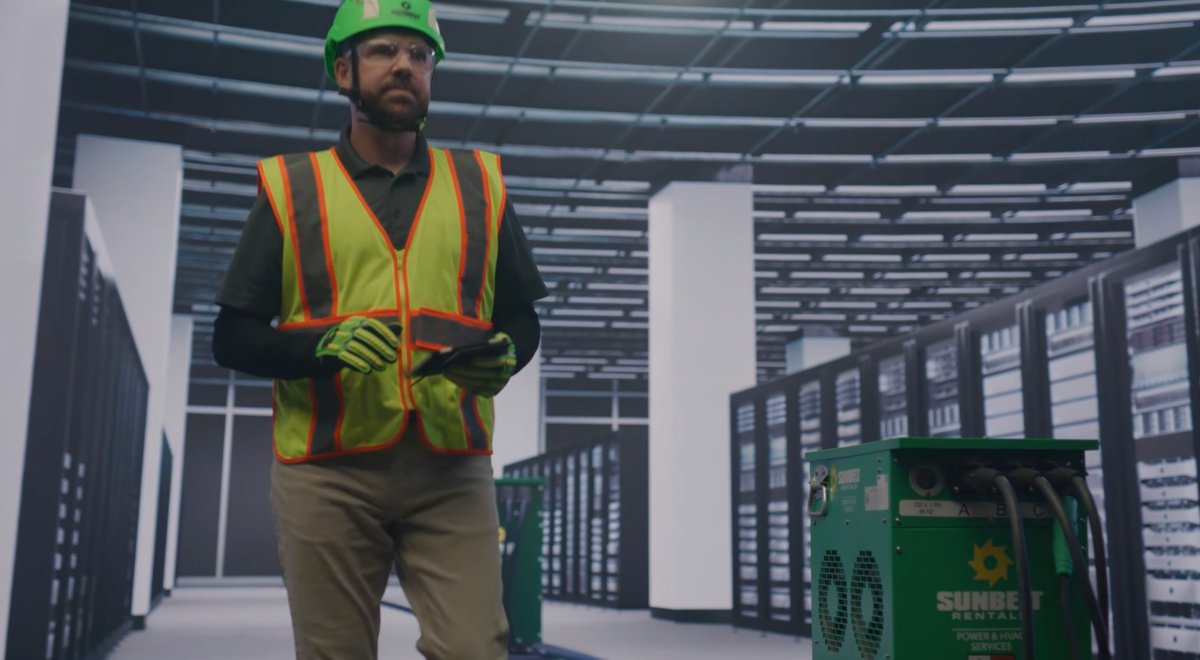 Someone wearing safety apparel walking inside of a data center.