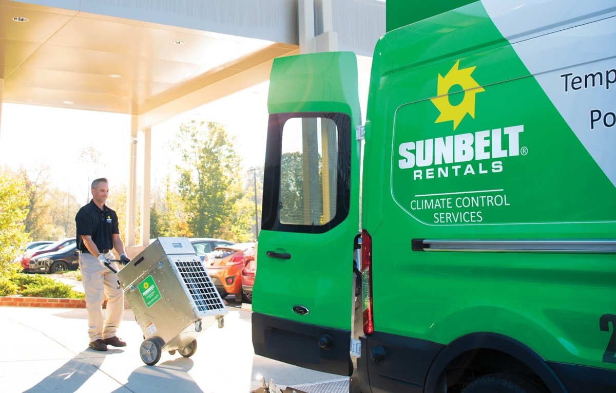 Sunbelt work wheeling equipment into rental truck.